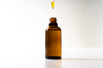 CBD oil or any other oil dropping into a small bottle - white background