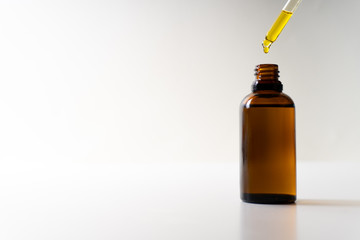 CBD oil or any other oil dropping into a small bottle - white background