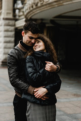 Attractive young couple walking near castle. Wife and husband kissing and holding hands on background of ancient building. Two smiling lovers. Family and love concept