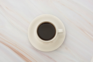 Coffee cup isolated on light, marble table. Top view, flat lay abstract black coffee drink with copy space.