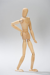 Wooden doll with hand on hip on grey background