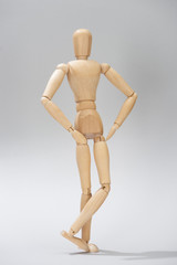 Wooden doll with hands on hips on grey background