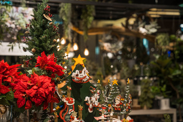Wooden rocking horse toy surrounded by Christmas tree and red flowers. Christmas decoration at the cafe indoor.