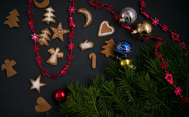 Christmas ginger cookies with white, sweet icing in the shape of Christmas trees, stars, angels and hearts on a dark concrete background with Christmas toys