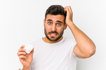Young caucasian man holding a moisturizer isolated being shocked, she has remembered important...