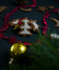 Christmas ginger cookies with white, sweet icing in the shape of Christmas trees, stars, angels and hearts on a dark concrete background with Christmas toys