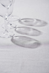 Transparent wine glasses with shadow on grey tablecloth