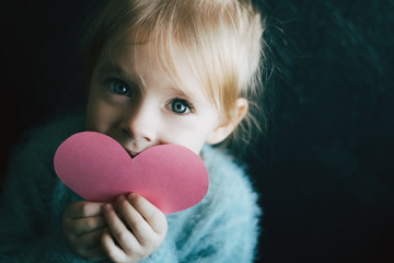 Snt. Valentines concept. Little girl holding paper heart. Love and people concept.Happy child with handmade paper pink heart 