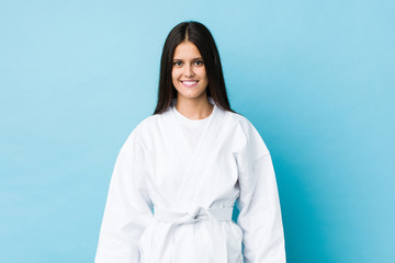 Young caucasian woman practicing karate isolated on a blue background