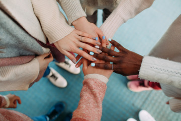 Hands of women of different races touch each other closeup.