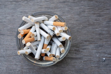 Cigarette butts that have been smoked in an ashtray on wooden table with space for text, Concept smoking area, Pollution from cigarettes
