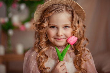 portrait of a beautiful curly girl with blond hair in a straw boater boater with tulips. waiting for the holiday on March 8