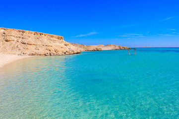 Fototapeta na wymiar Orange Bay Beach with crystal clear azure water and white beach - hammock in the water for relaxing - paradise coastline of Giftun island, Mahmya, Hurghada, Red Sea, Egypt.