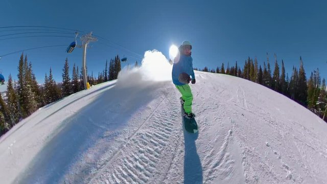 Selfie stoked snowboarder shredding the groomed ski slopes sprays snow at the camera