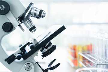 Closeup of microscope lens with test tube in rack background. Scientist and technology concept.