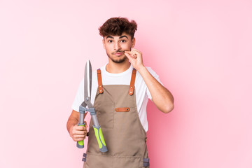 Young arab gardener man isolated with fingers on lips keeping a secret.