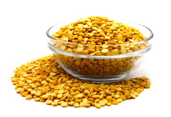 Yellow lentil in glass bowl isolated on white background with clipping path. To prepare a traditional vegetarian Indian spiced soup-puree chana dal.