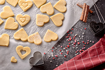 Fototapeta na wymiar top view of homemade heart-shaped cookies on black background
