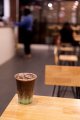 iced mint chocolate drink in plastic glass, put on a wooden table