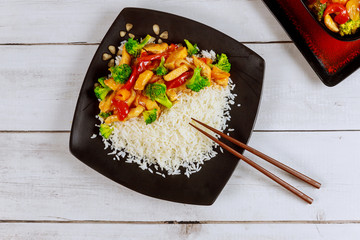 Japanese dish stir fry chicken with rice and vegetable on square plate with chopstick.