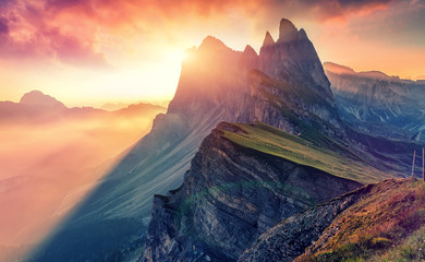 Colorful evening Scene at Gardena valley during sunset. Bright sky over the Seceda peak glowing Sunlight. Amazing Nature Landscape. Sass Rigais and Furchetta mountains. Geisler Group. Dolomites Alps - obrazy, fototapety, plakaty