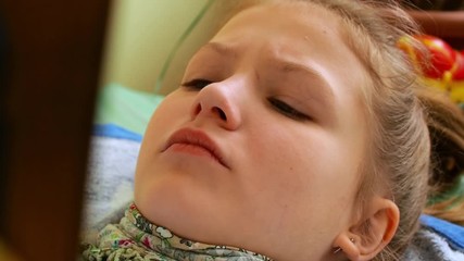 Girl with ascarf on neck reads in bed wiating for doctor