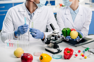 cropped view of molecular nutritionists holding test tubes and food