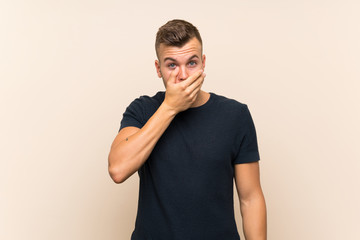 Young handsome blonde man over isolated background covering mouth with hands