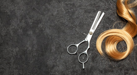 The hairdresser. Scissors and curl of hair on a black background