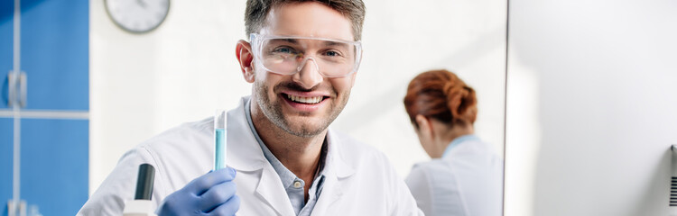 Fototapeta premium panoramic shot of smiling molecular nutritionist holding test tube
