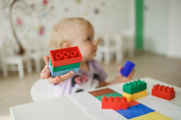 Children gathering building blocks in the kindergarten. Educational games and toys. Close up.