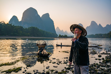An old fisherman standing by the river in sunset