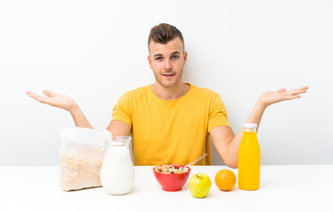 Young blonde man having breakfast having doubts with confuse face expression