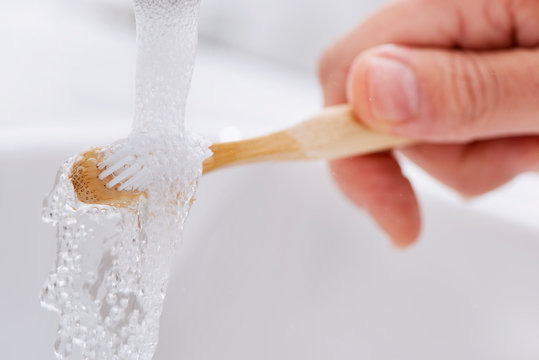 Man Using A Bamboo Toothbrush In The Bathroom