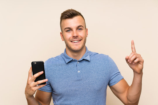 Young blonde man using mobile phone pointing up a great idea