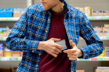 the kleptomania concept, a man in the grocery store stealing food and put it in the pocket