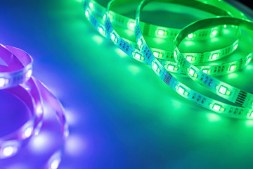 Bright neon LED strip glows purple, violet and green. Copyspace.