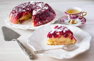 Piece of cranberry tart, pie, cake on plate, tea spoon, cup of tea on white wooden table backgound