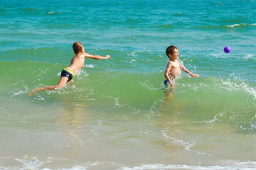 Two brothers splashing in the sea. Funny kids in the ocean. Family resort vacation