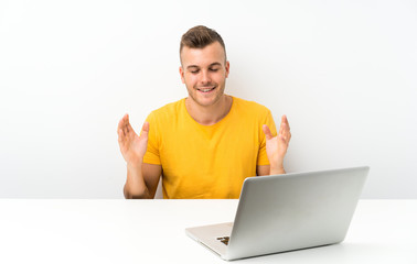 Young blonde man in a table with a laptop laughing