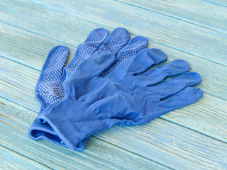 Fototapeta na wymiar Blue construction gloves on wooden plank background close-up