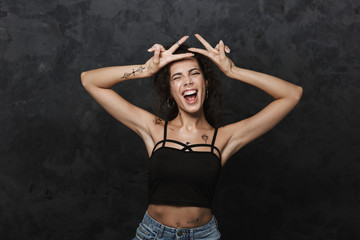 Image of young joyful woman laughing and gesturing peace sign