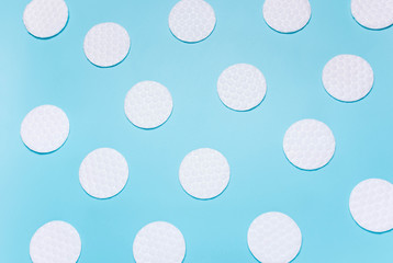 White cotton disks on blue background. Concept of cleanliness, makeup, body care.