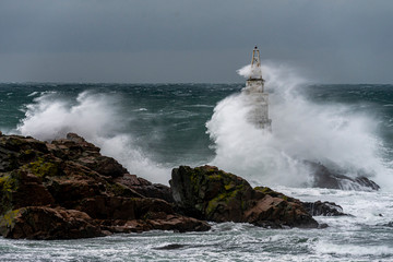 Dramatic seascape. Huge waves hit the lighthouse during severe sea storm. 
