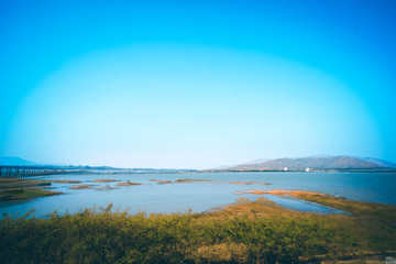 Panorama of lake landscape in Thailand with railway across the lake and mountain scene on background  against summer blue sky in Lopburi province Pa Sak Jolasid Dam