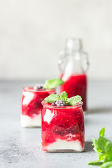 Glass jars of healthy layered berries and yogurt smoothie. Mix berry smoothie with raspberry, blackberry and yogurt. Wellbeing and weight loss concept. Selective focus, toned image.
