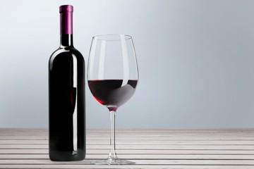 Red wine glass on wooden desk at wall background