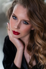 Fototapeta na wymiar Portrait of a beautiful blonde girl with red lips and evening makeup, wavy hair wearing a black velvet jacket. Healthy, clean skin. Close-up. Advertising, commercial design.
