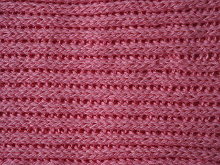 Knitted fabric texture. Pink color. English knitting with front and back loops. Knitting on the knitting needles. Horizontal lines.