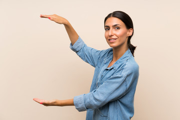 Young woman over isolated background holding copyspace to insert an ad